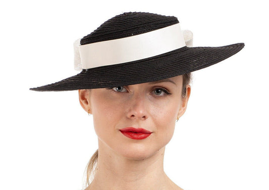 Woman wearing a black hat with a white band on a white background